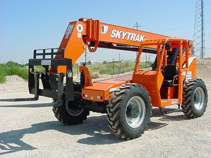 An orange skytrax forklift is parked on a gravel road
