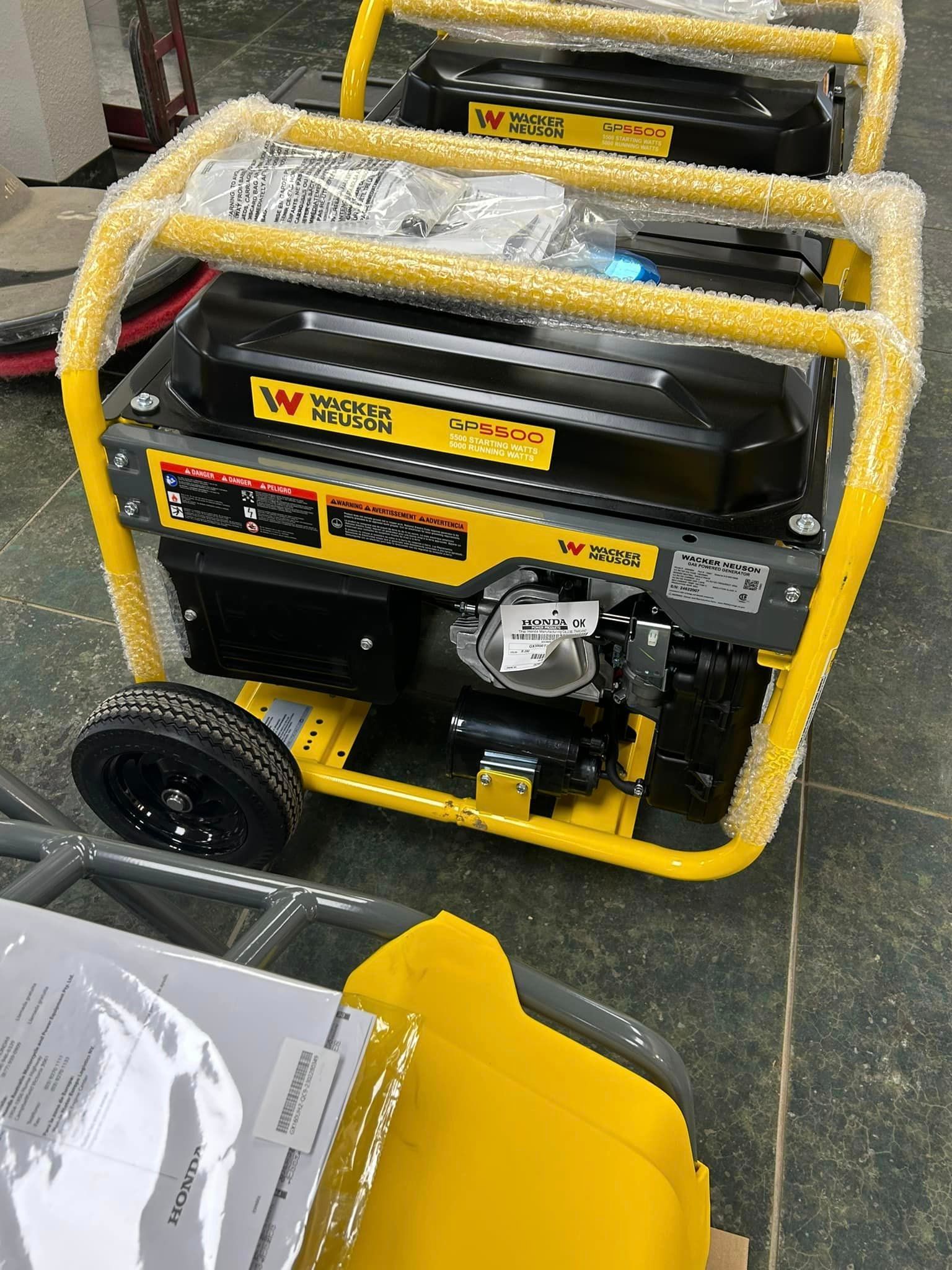A yellow and black generator with wheels is sitting on a tiled floor.