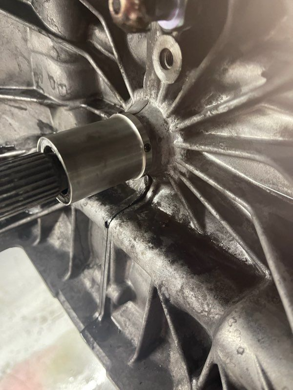 Close-up of a metal part with a shaft, possibly automotive. The part is dark and has a circular structure.