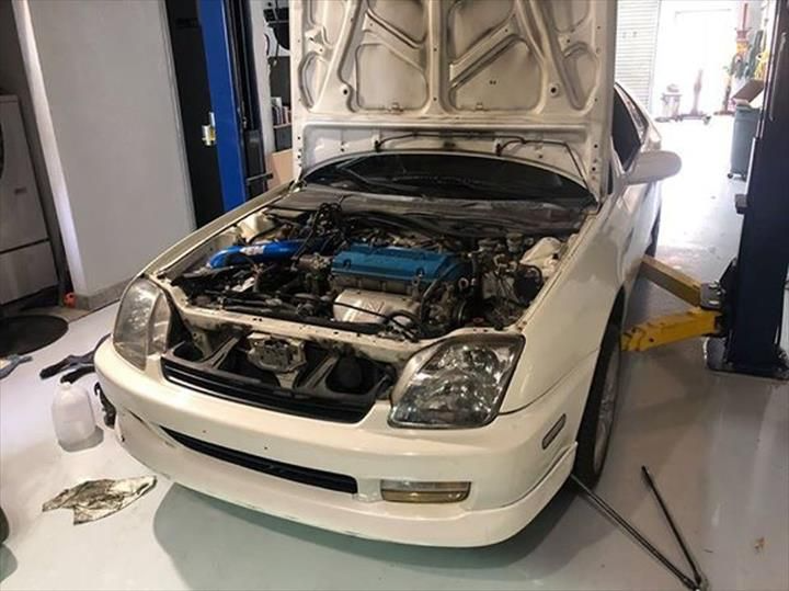 White Honda Prelude with open hood in a garage being worked on.