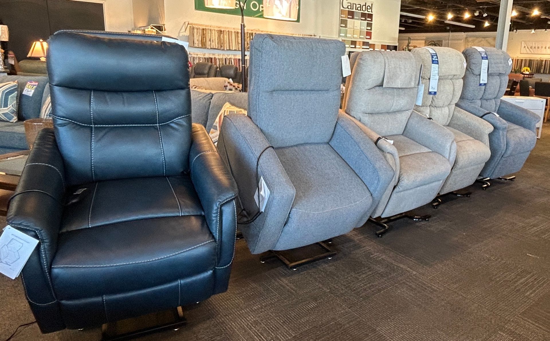 Row of black and gray reclining theater seats displayed in a showroom.