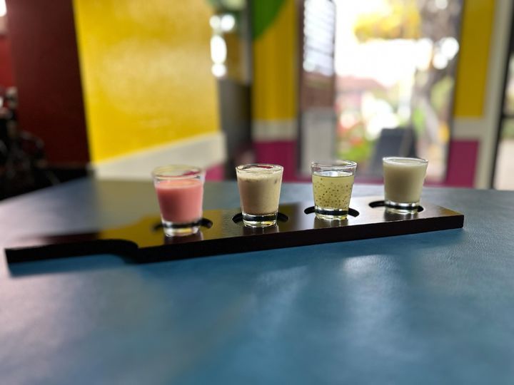 Four shot glasses are lined up on a tray on a table
