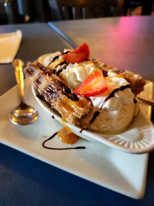 A dessert with whipped cream and strawberries on a plate with a spoon