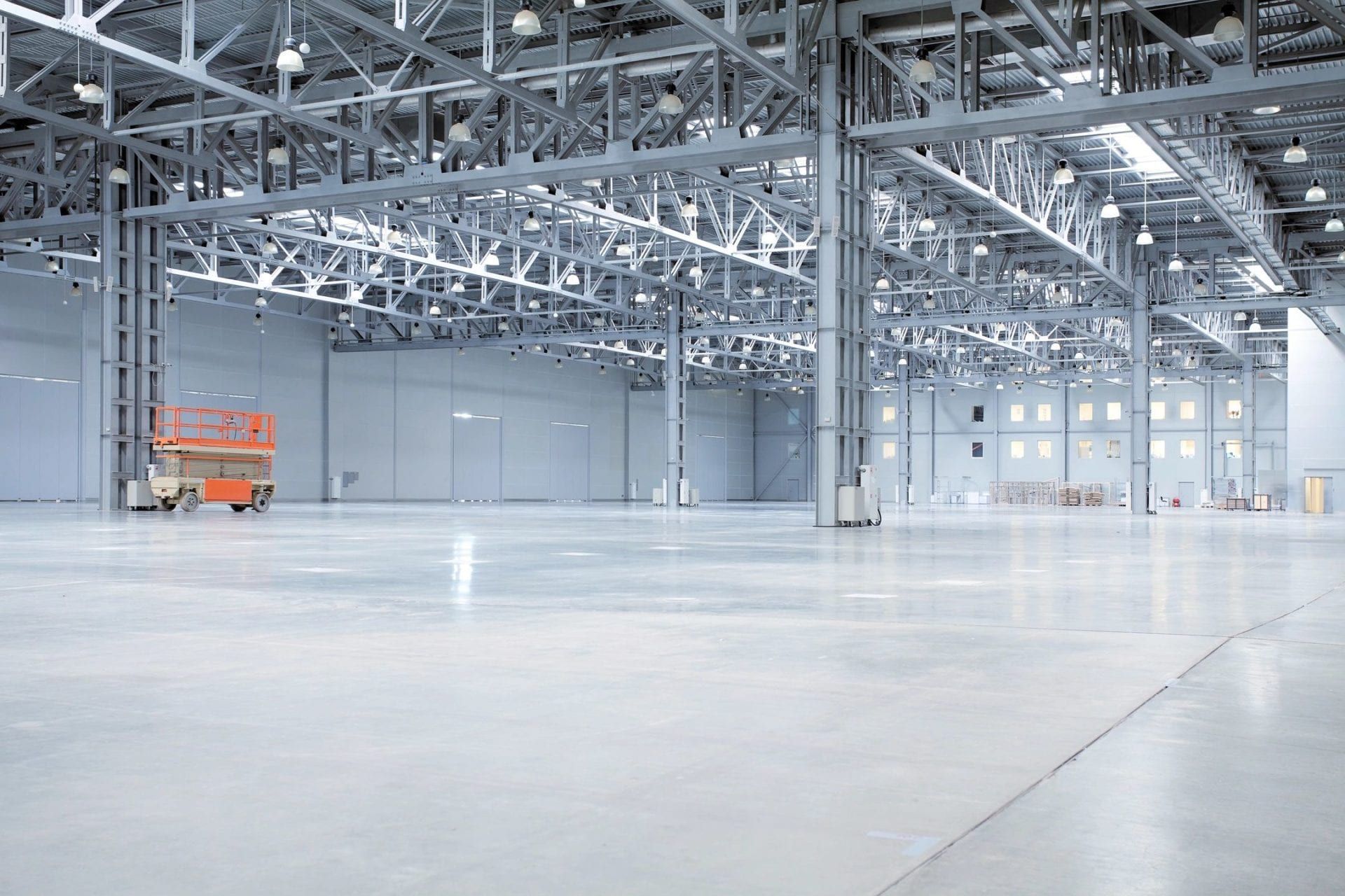 An empty warehouse with a concrete floor and a forklift in the background.