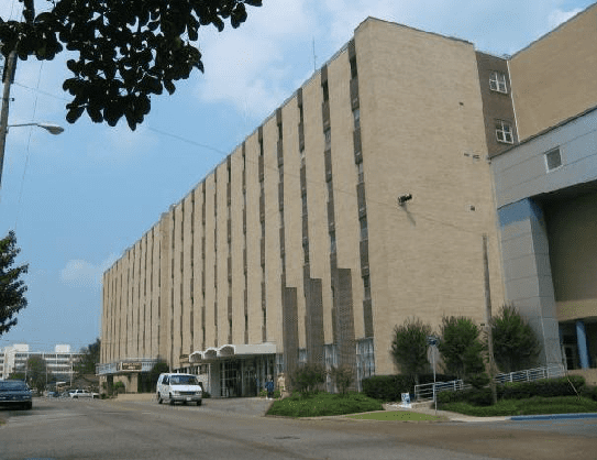 A white van is parked in front of a large building