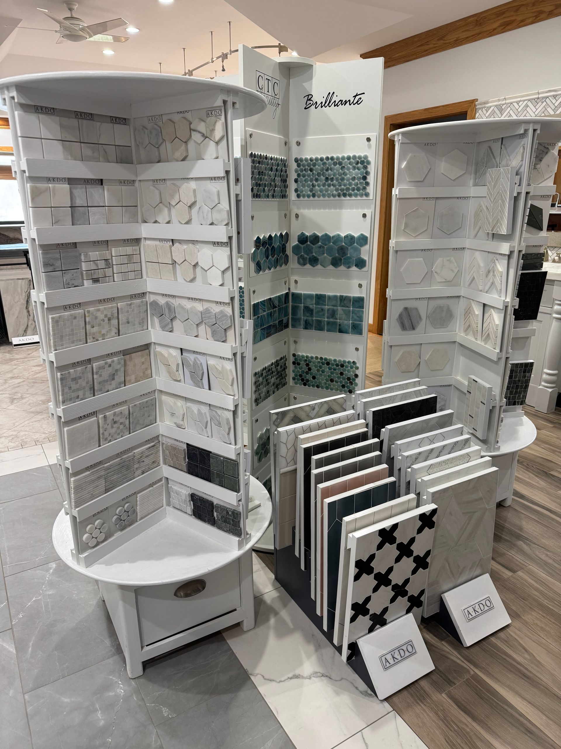 Display of various tiles on rotating stands in a store. Various colors, textures, and patterns are showcased.