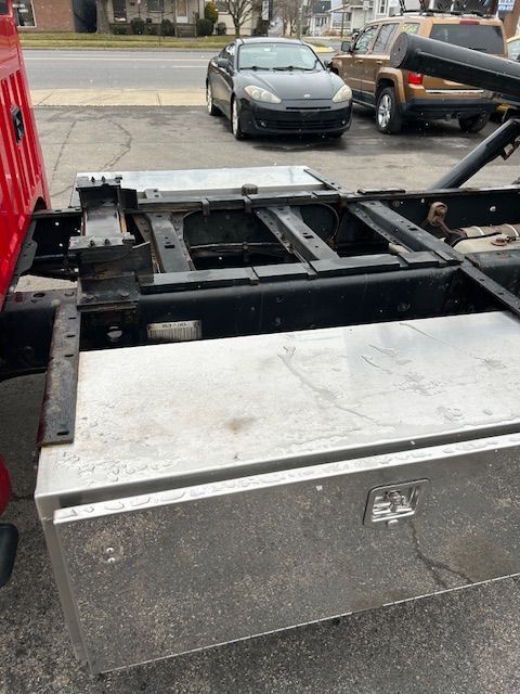 Atow truck is parked on the side of the road next to a car.