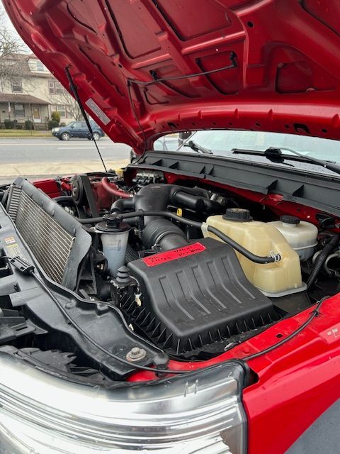 The engine of a red truck is shown with the hood open