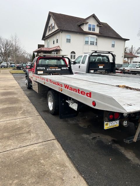A tow truck with a flat bed is parked in front of a house.