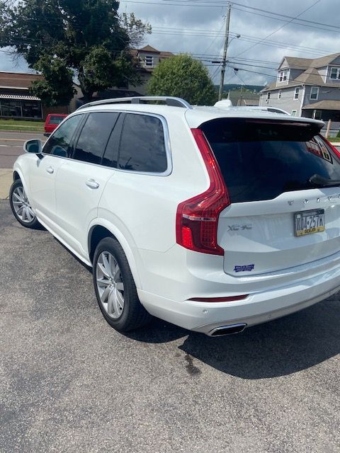 A white Volvo XC90 is parked in a parking lot.