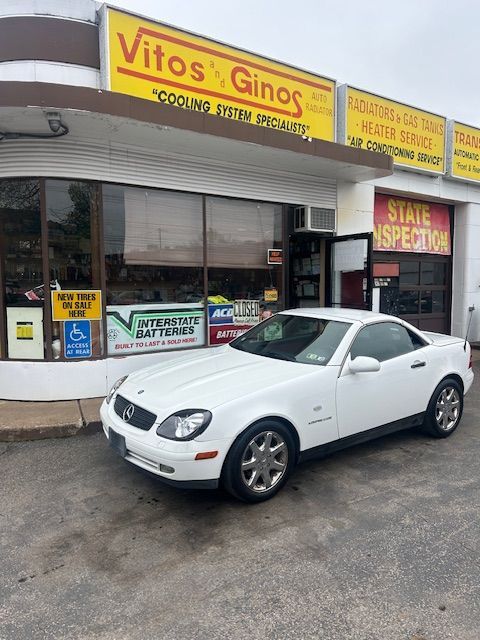 A white car is parked in front of a car dealership