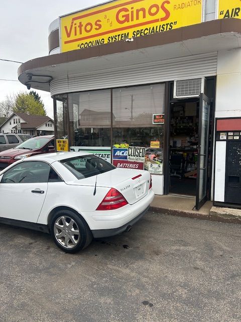 A white car is parked in front of a store called Vitos and Gino's