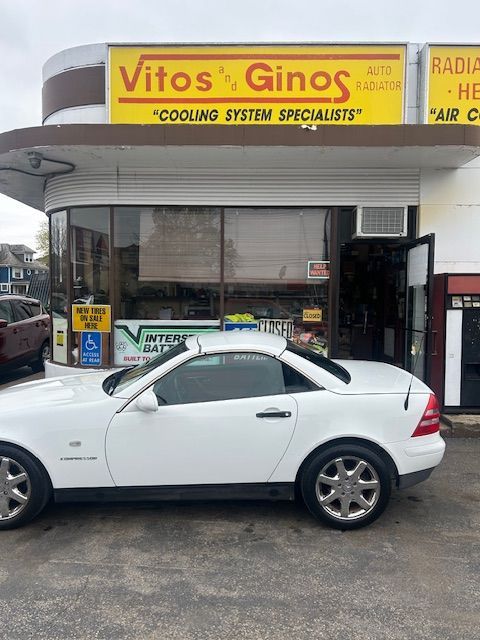 A white car is parked in front of a store called Vitos and Gino's