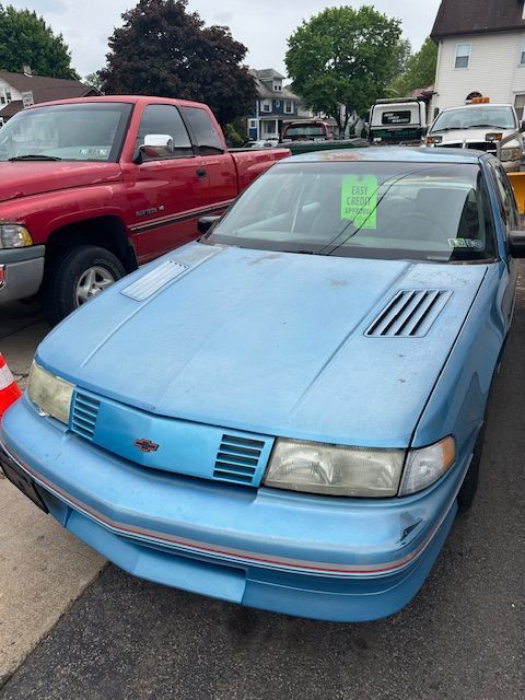 A blue car is parked next to a red truck