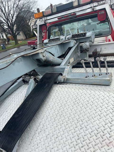 a red and white tow truck is parked on the side of the road .