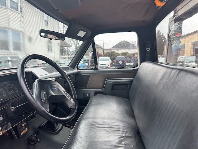 the interior of a 1989 Ford F-450 with a black seat and steering wheel