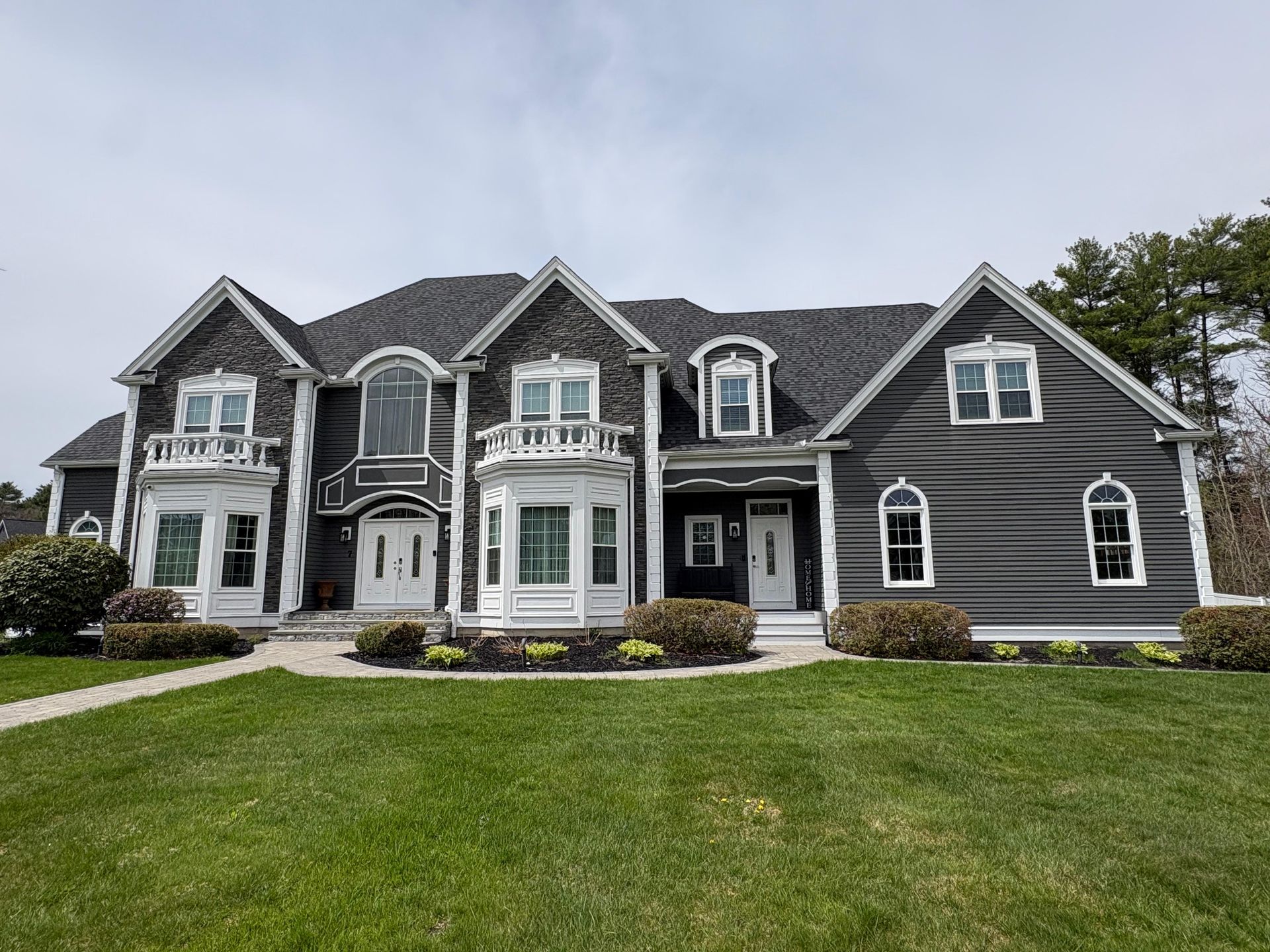 Large gray suburban house with white trim and a manicured green lawn