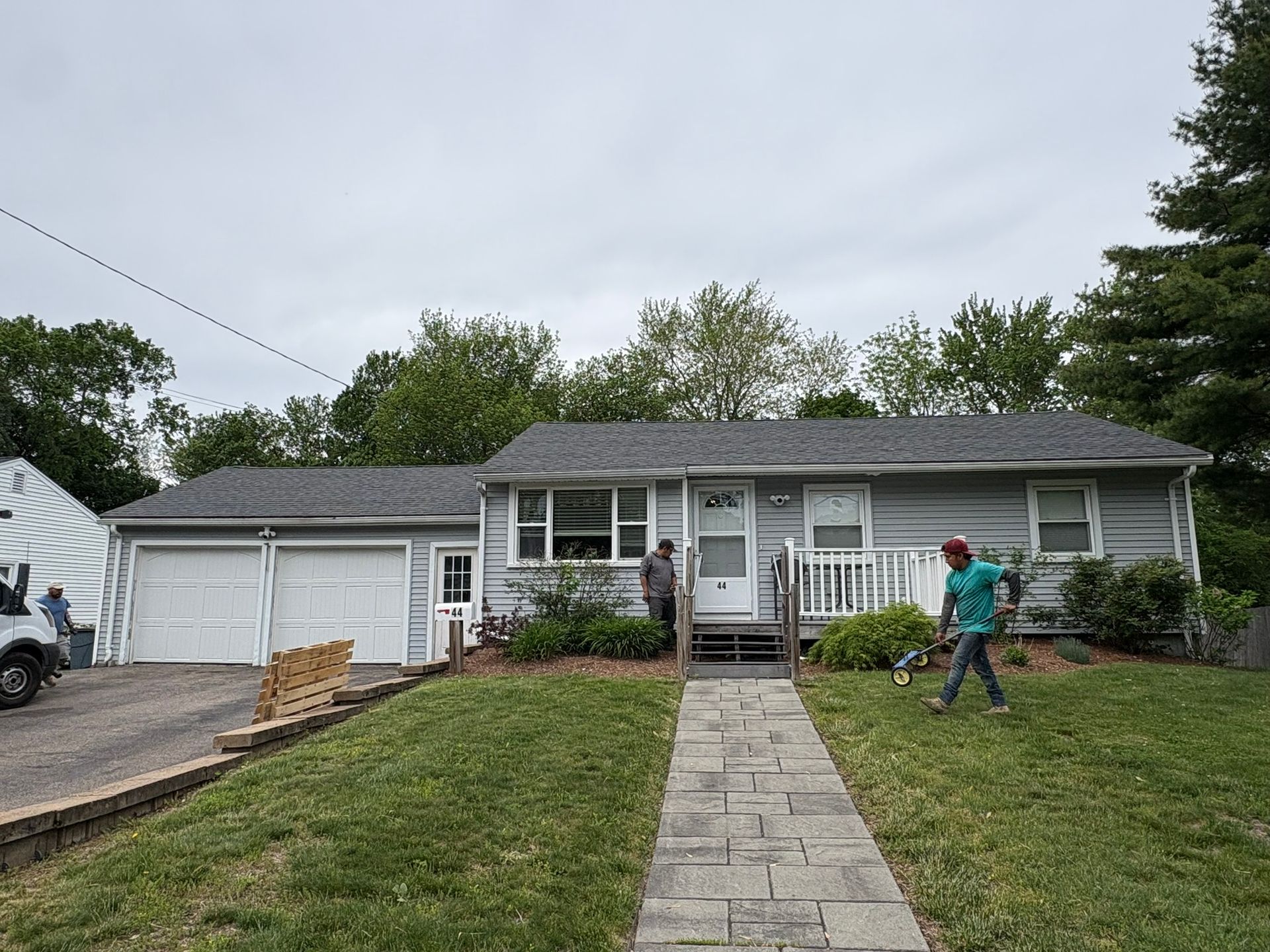 Single-story gray house with a front walkway, garage, and a person working near the porch