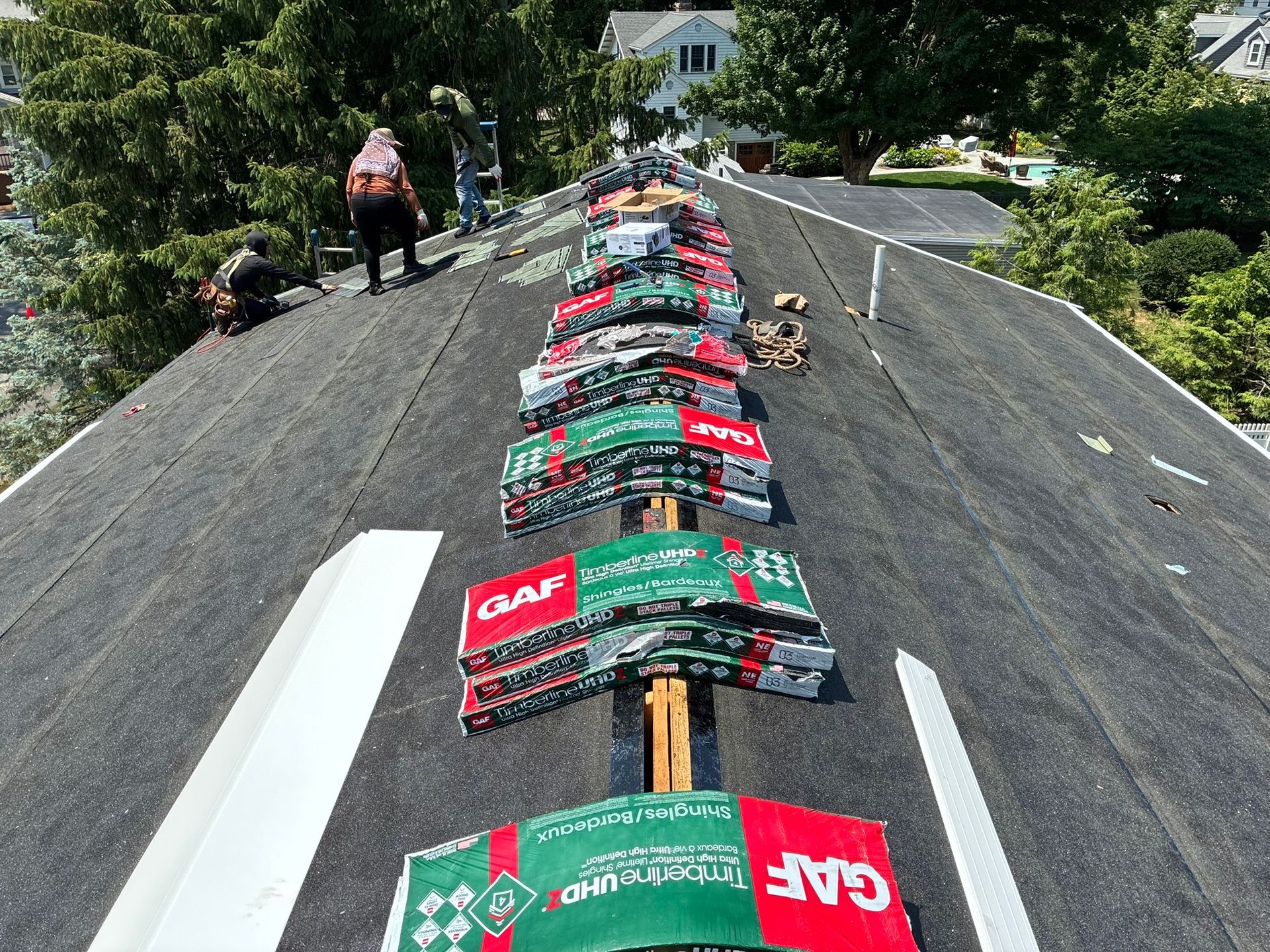 Roofing workers installing colorful shingles on a steep house roof