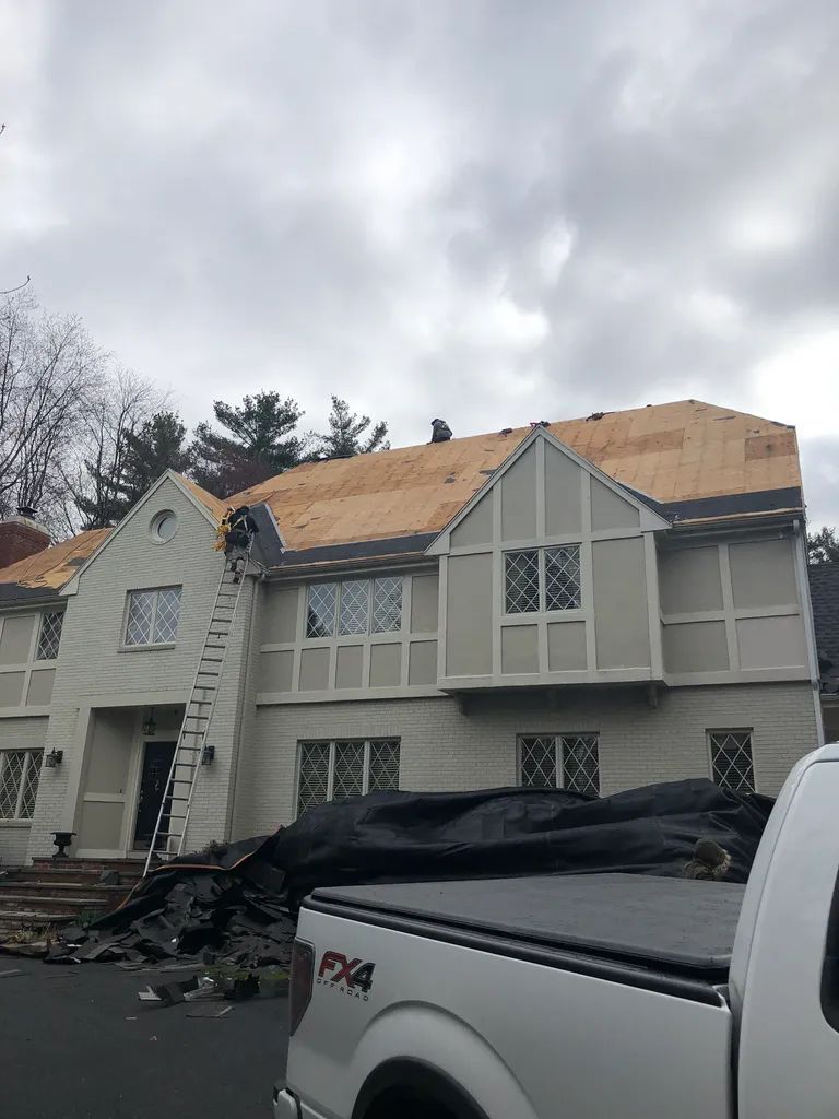 Partially roofed house after storm damage with a pickup truck in the driveway
