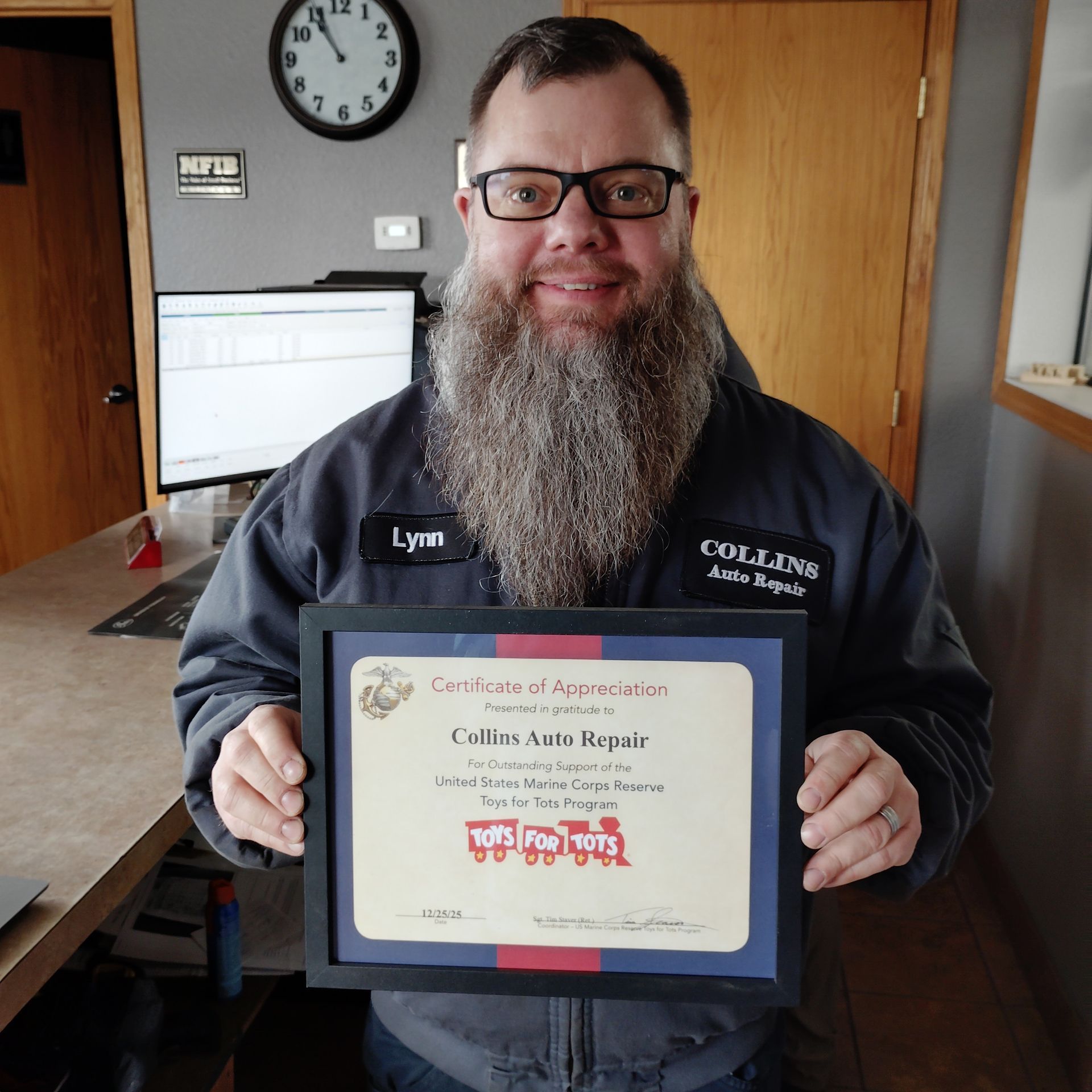 Man holding a framed certificate and smiling in an office