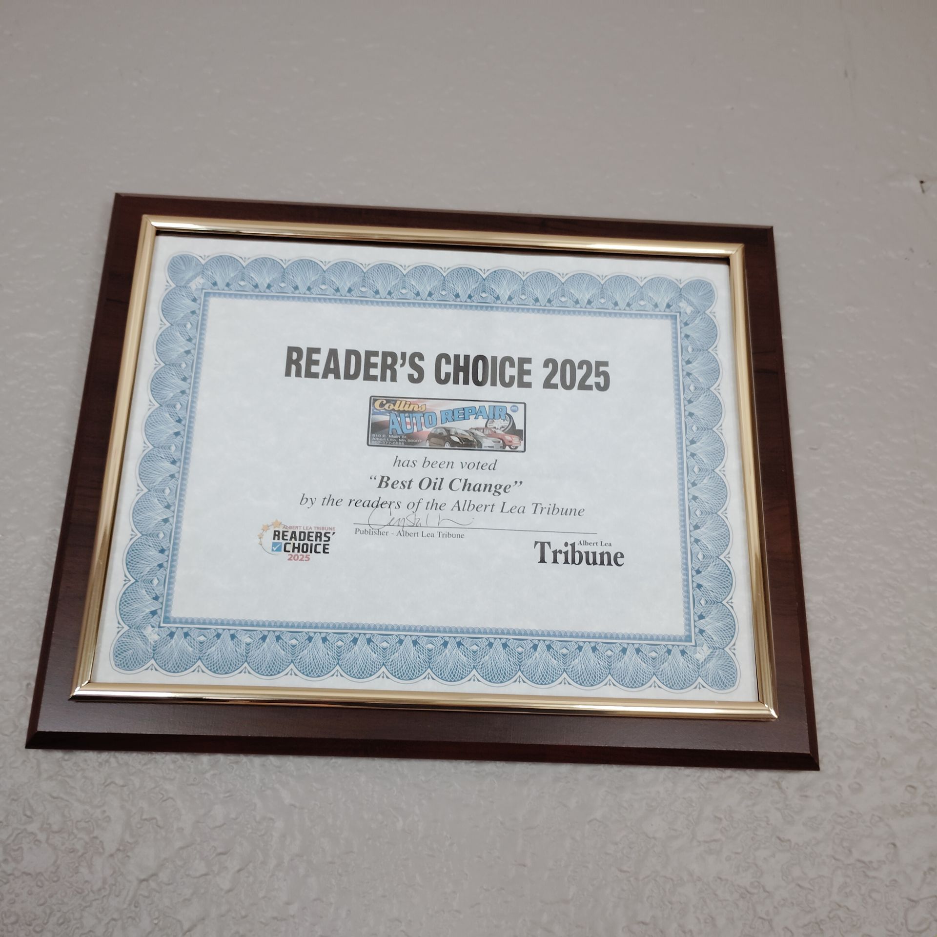 Framed Reader’s Choice 2025 award certificate on a wall with a blue border and wood frame