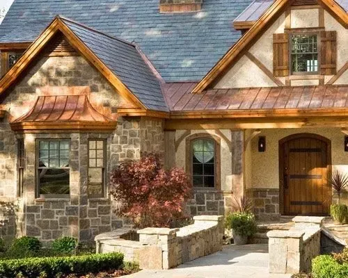 Stone-and-wood house exterior with gabled roof, arched porch, and landscaped entryway.