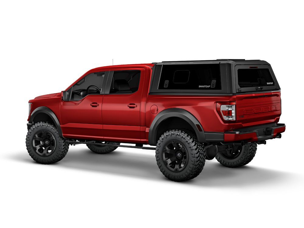 Red Ford Raptor pickup truck with black cap and large tires.