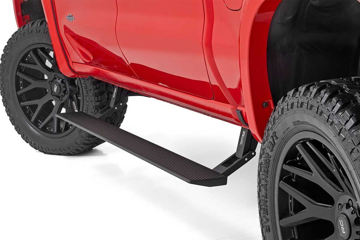 red truck with black side steps and large black tires