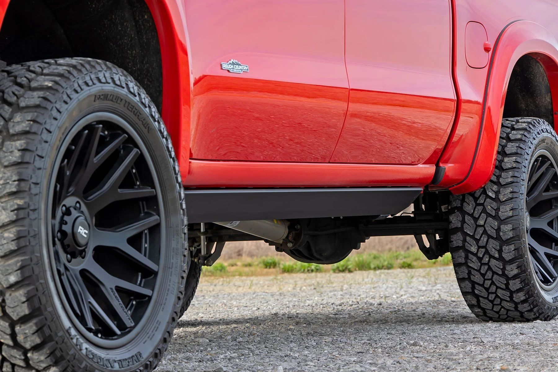 red truck's side profile with black wheels and tires, rear axle and running boards visible