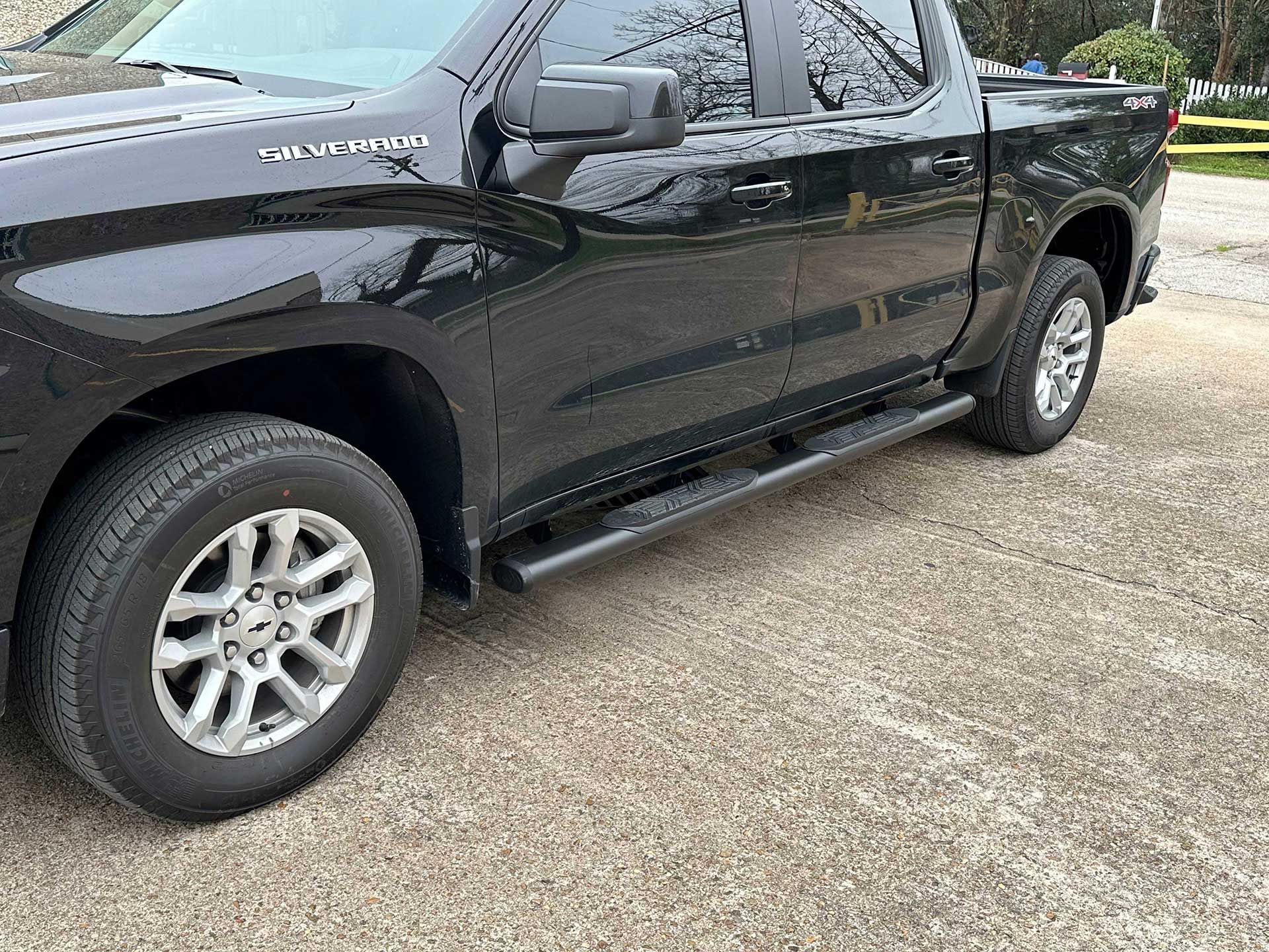 red pickup truck with a black retractable tonneau cover and side step