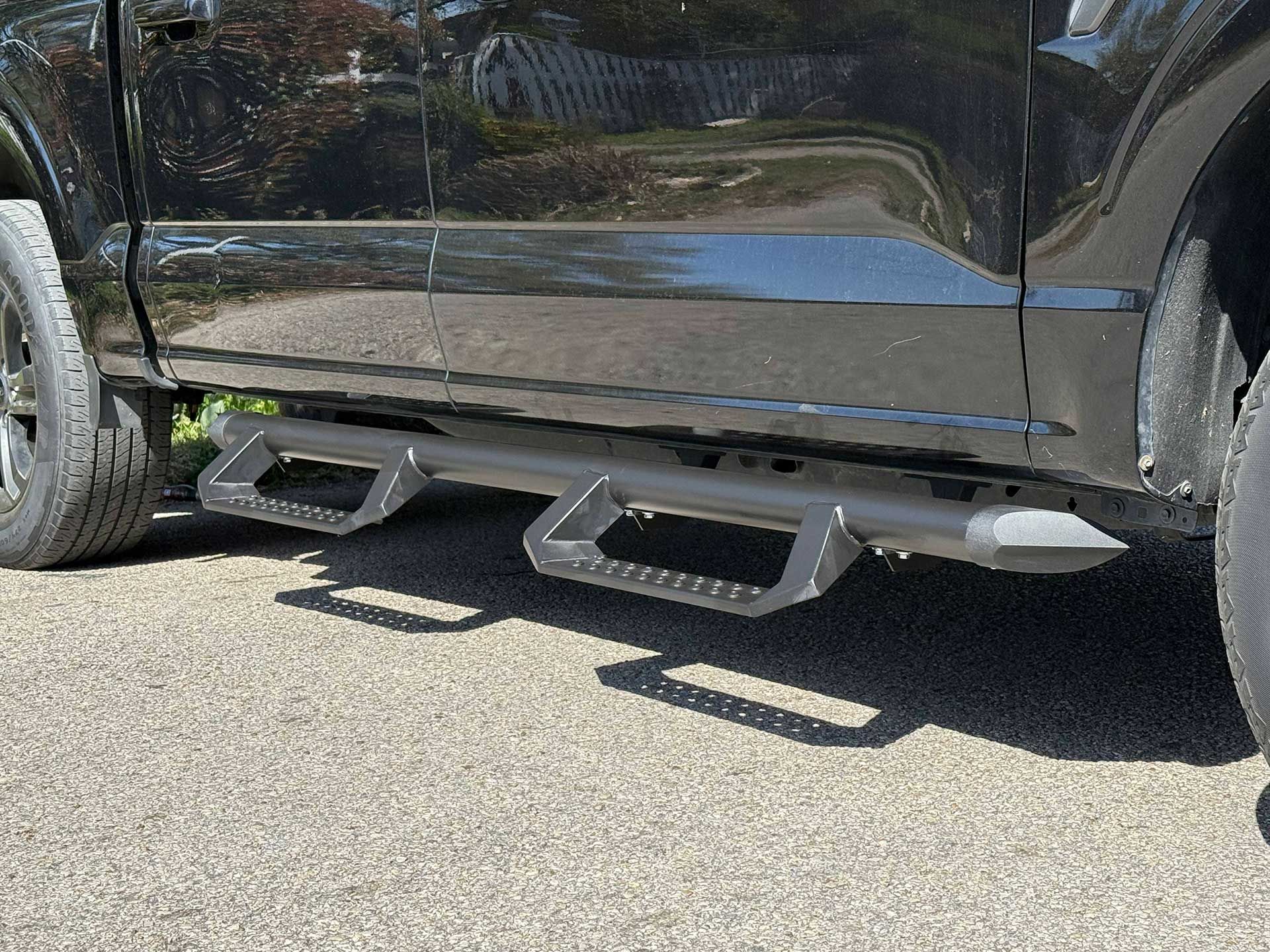 black truck with step bars, parked on asphalt