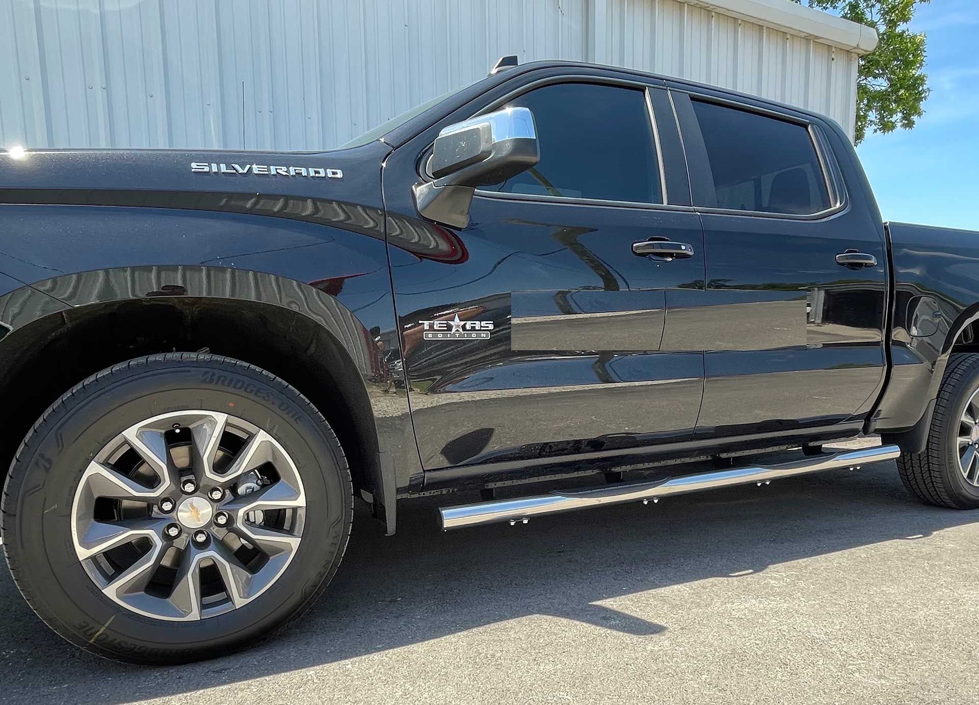 black Chevy Silverado pickup truck parked with tinted windows and running boards