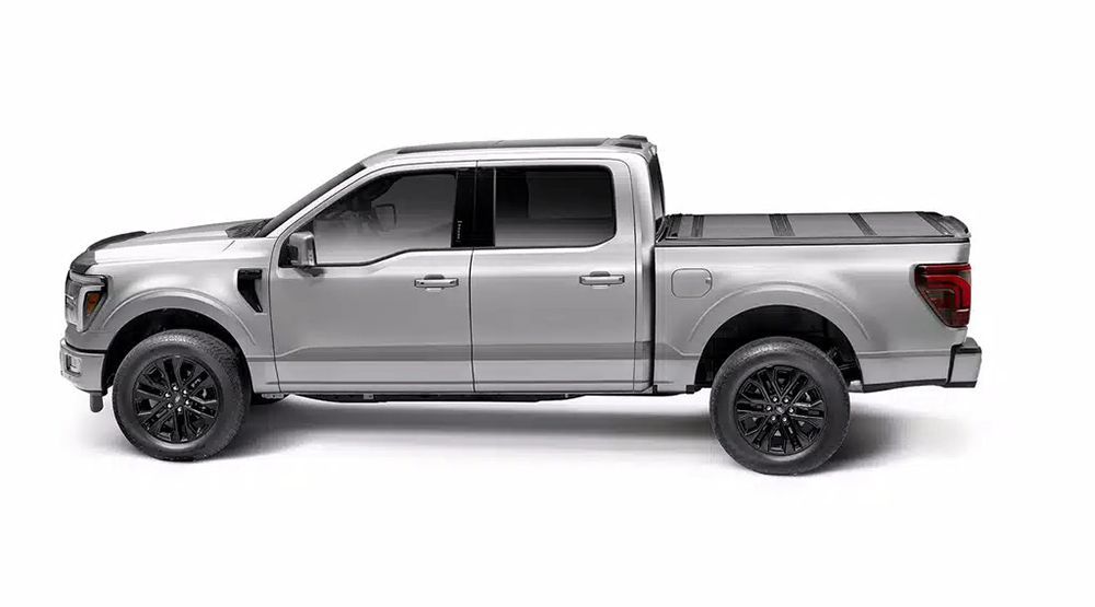 Silver Ford pickup truck with black wheels and a closed bed cover.