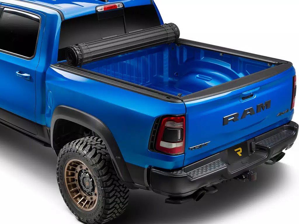 Blue Ram truck with a black rolling tonneau cover.