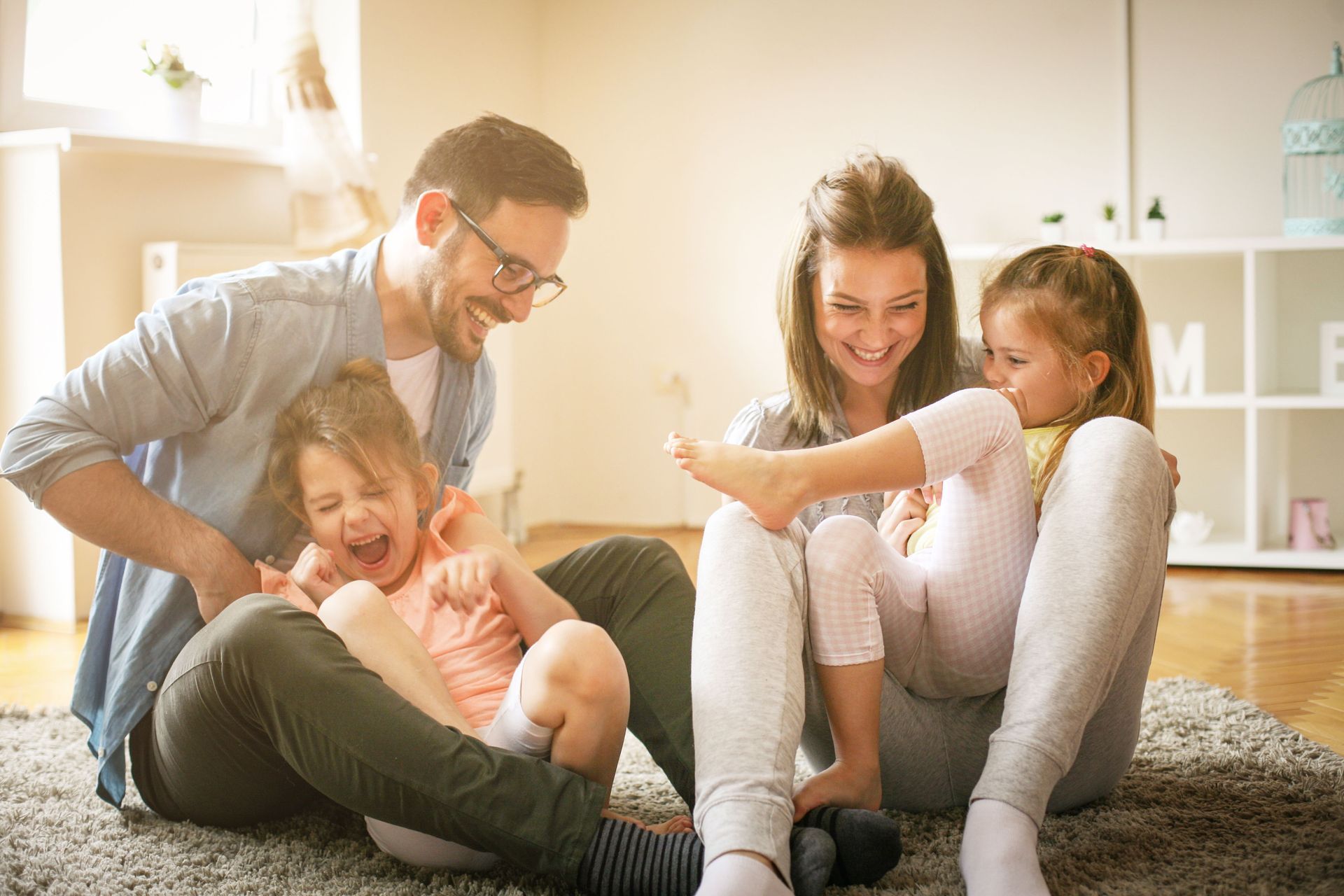 A family is sitting on the floor playing with their children.