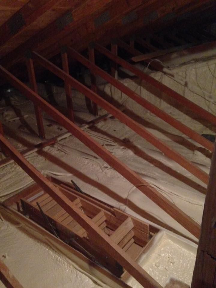The attic is being insulated with foam and wooden beams.