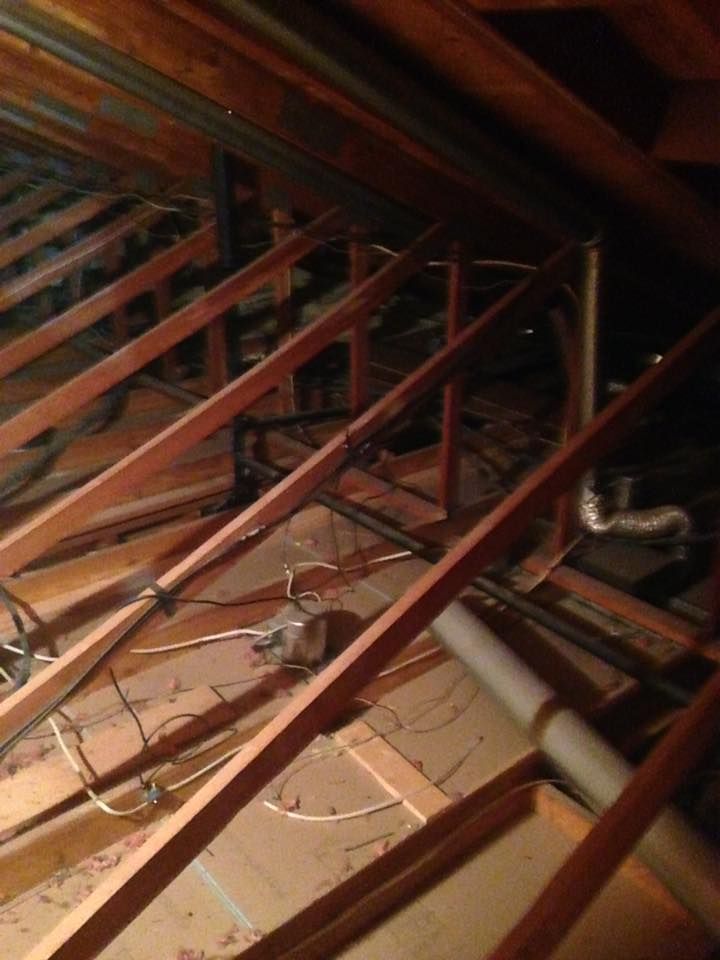 An attic with a lot of wooden beams and pipes.