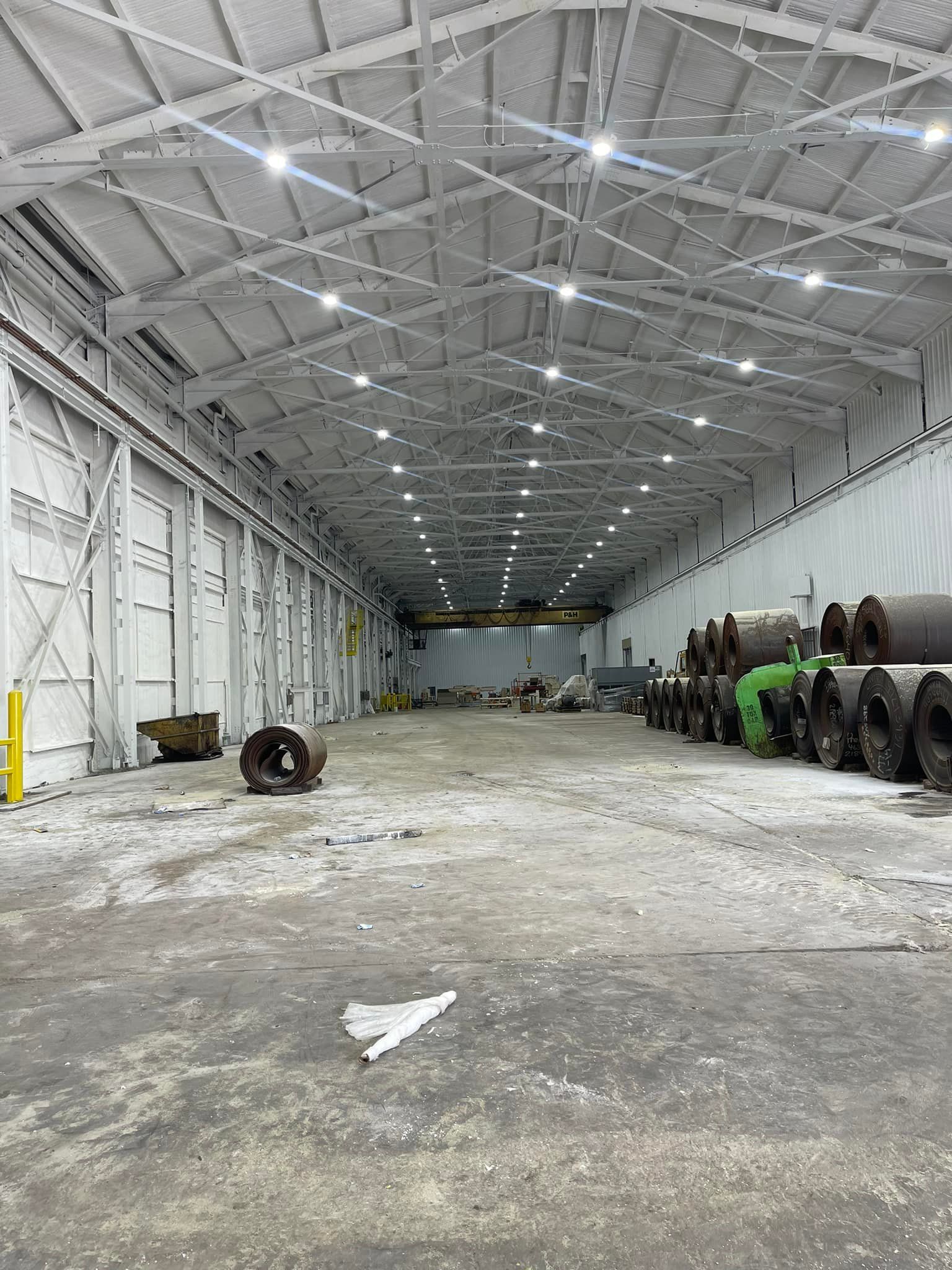 A large warehouse filled with lots of pipes and a crane.