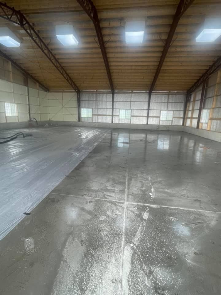 A large empty warehouse with a concrete floor and a wooden ceiling.