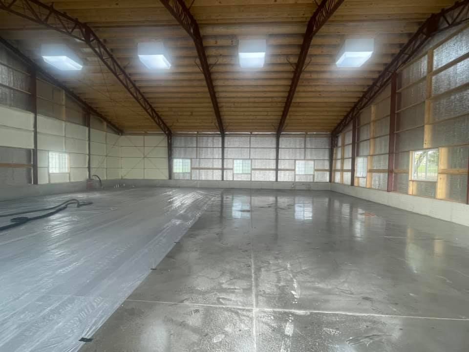 A large empty warehouse with a lot of windows and a concrete floor.