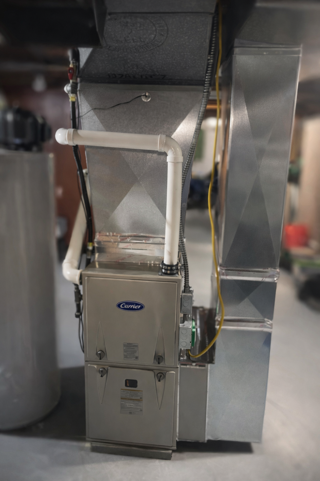 A Carrier furnace with attached ductwork and pipes in a basement.