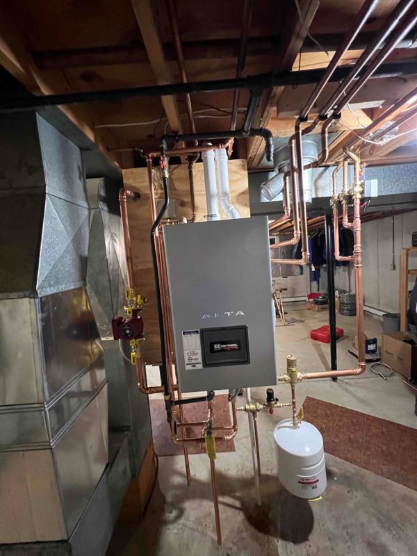 Copper pipes and a gray water heater in a basement setting.