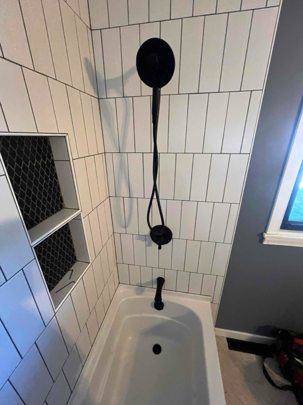 Bathroom with white subway tile, black fixtures, and a built-in shelf.