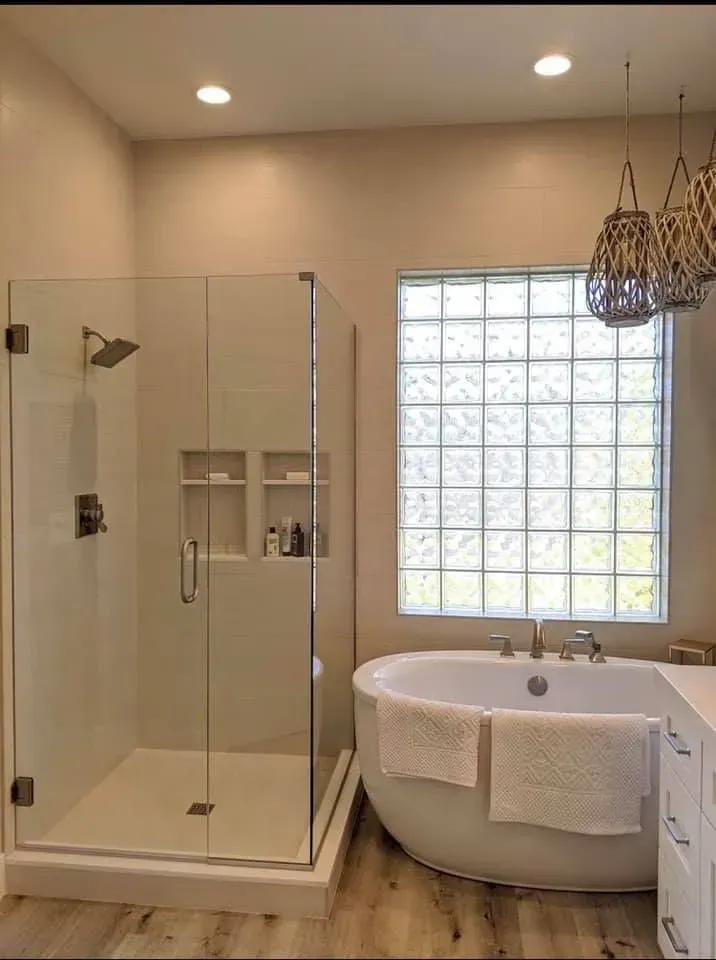 Modern bathroom with glass shower, freestanding tub, and glass block window