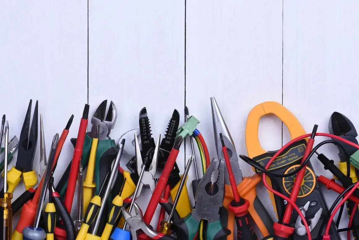 Assorted hand tools with red and yellow handles in a container against a white background