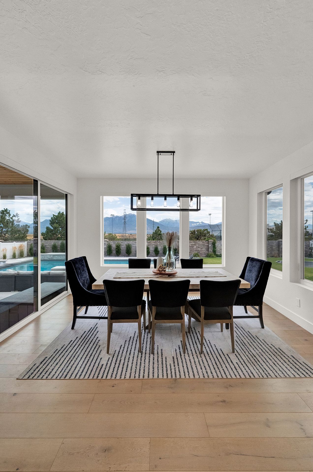 A dining room with a table and chairs and a rug.