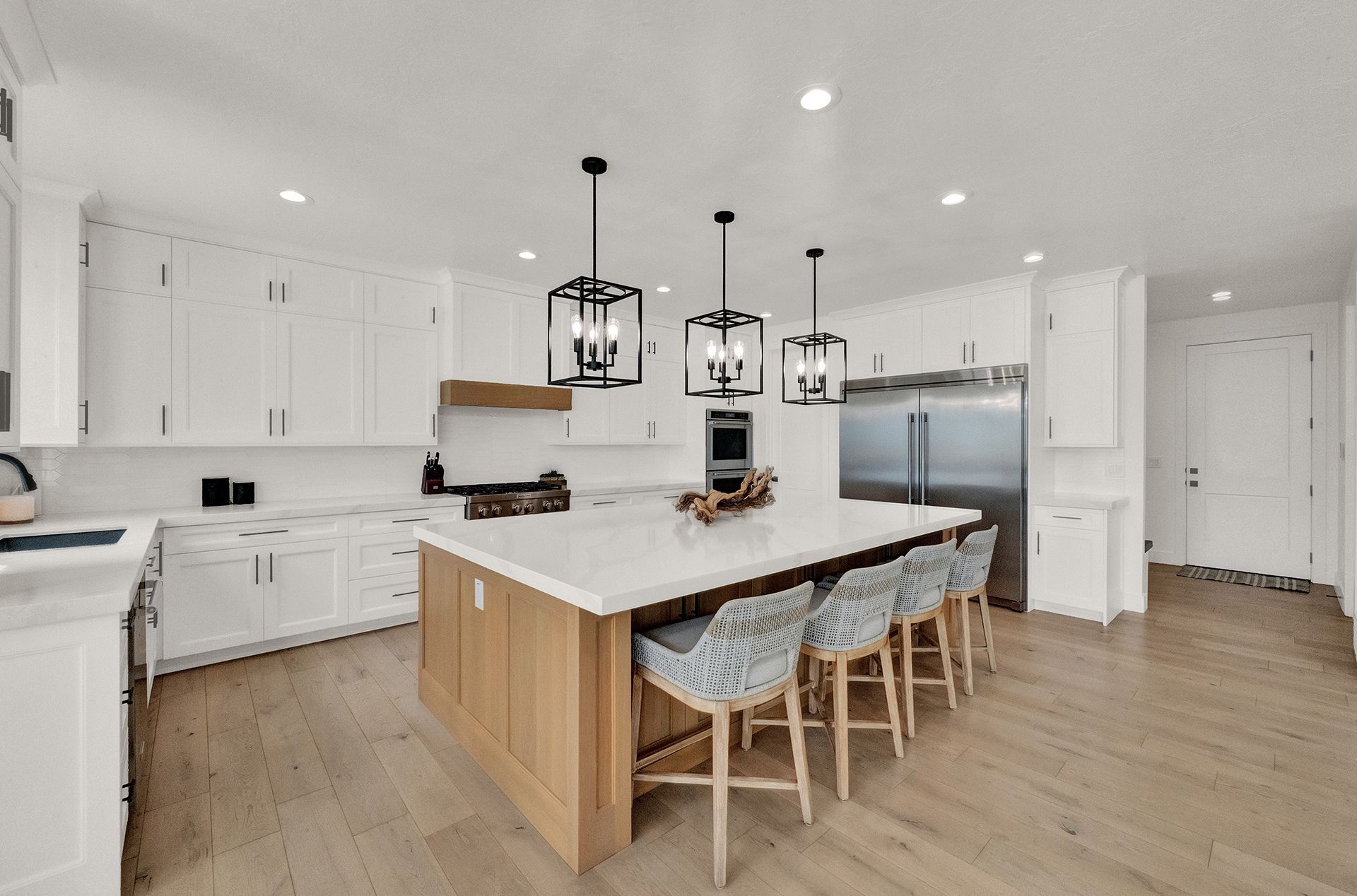 A kitchen with white cabinets , stainless steel appliances , and a large island.
