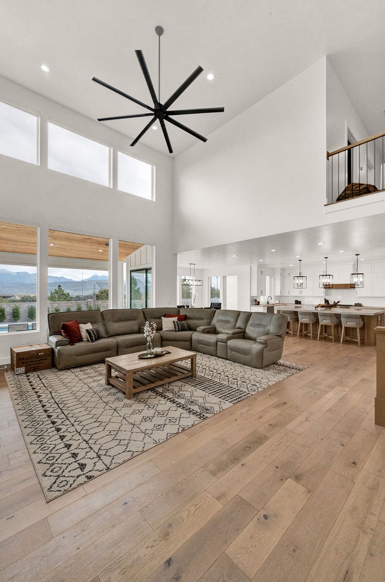 A living room with a large sectional couch and a ceiling fan.