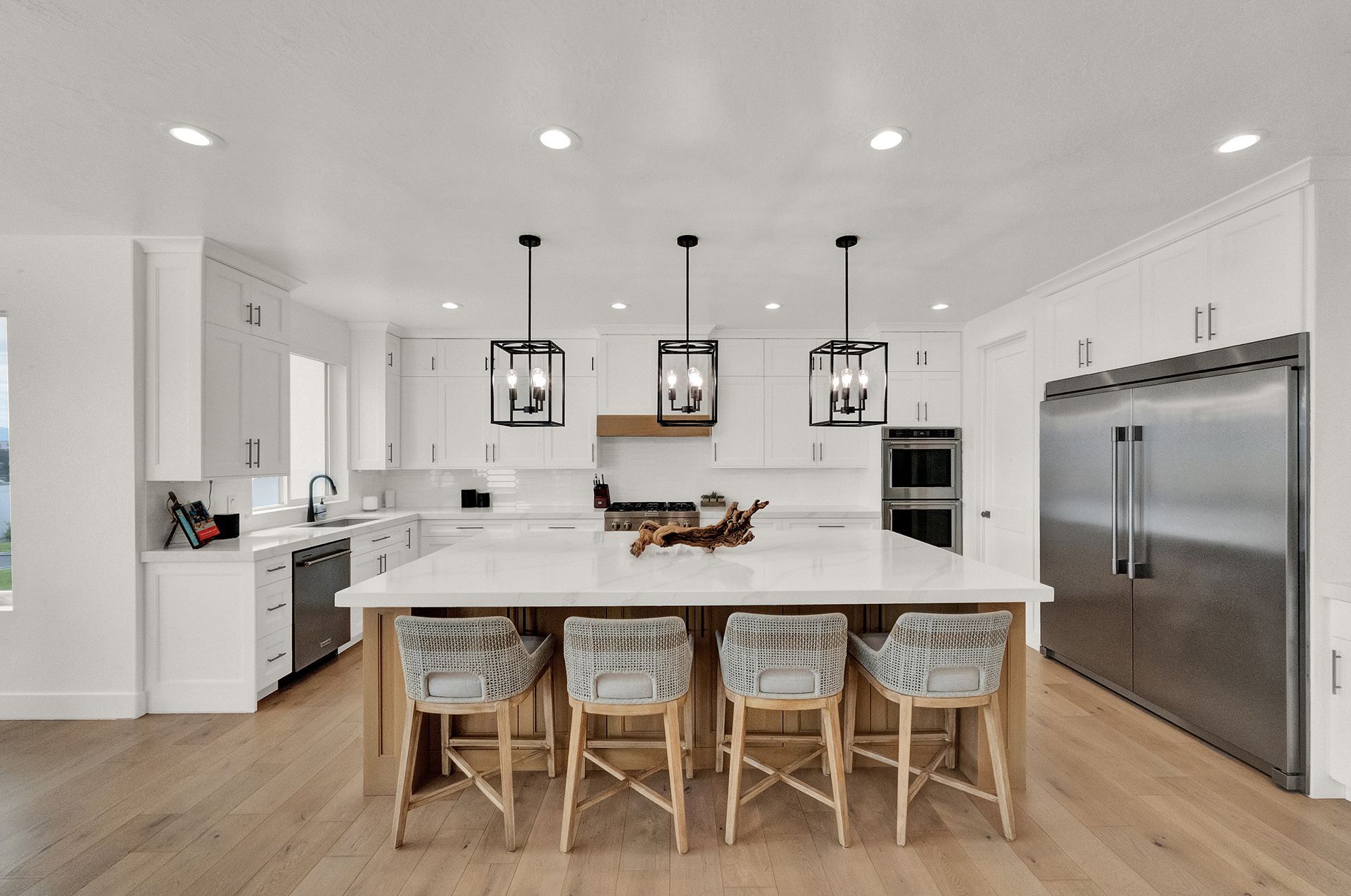 A kitchen with white cabinets , stainless steel appliances , and a large island.